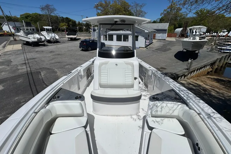 Slide: The Image of 2026 Edgewater 262CC boat with spacious seating, docked at a marina under clear skies. - 34