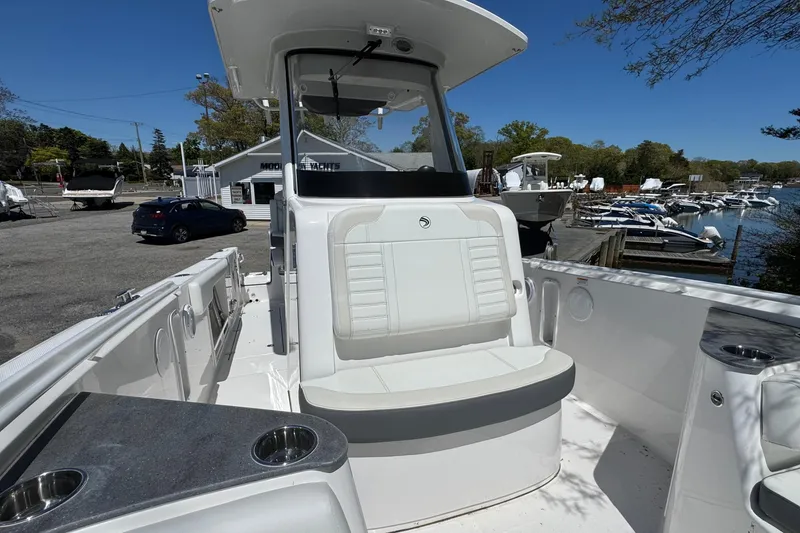 Slide: The Image of 2026 Edgewater 262CC boat interior with seating and cup holders, docked at a marina. - 35