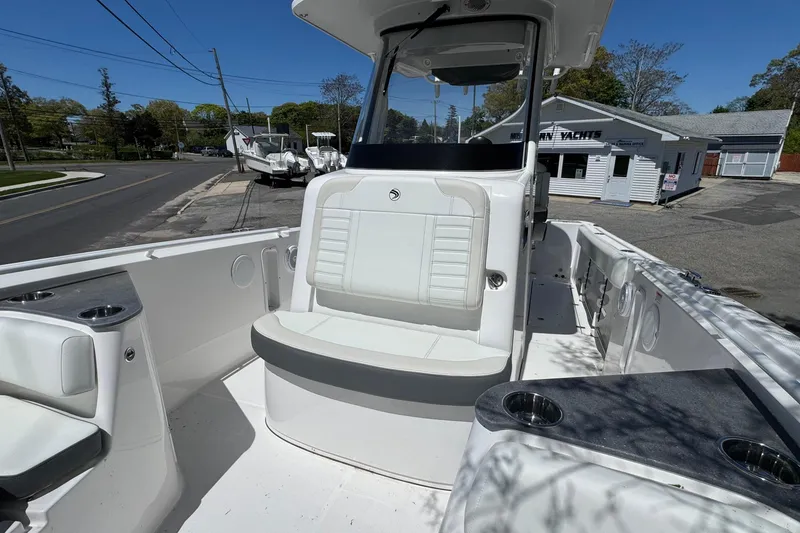 Slide: The Image of 2026 Edgewater 262CC boat interior with seating and cup holders, docked near a yacht dealership. - 37
