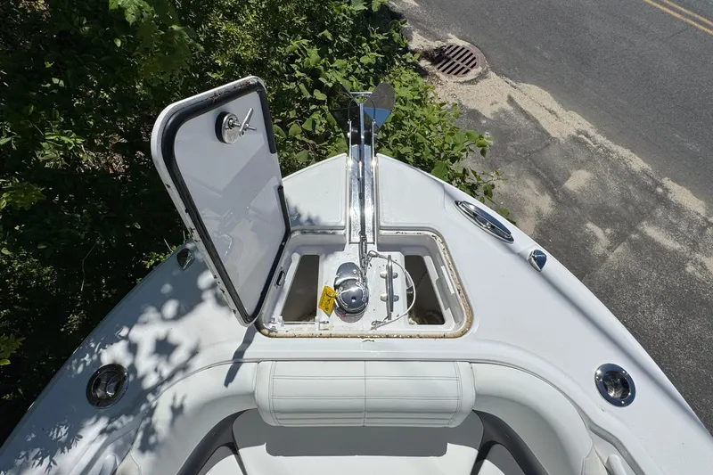 Slide: The Image of Bow of 2026 Edgewater 262CC boat with open anchor hatch, surrounded by greenery. - 39
