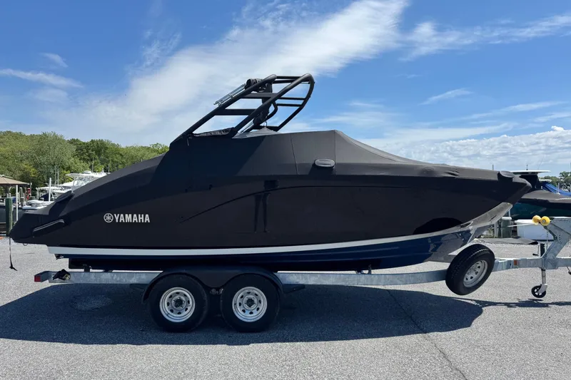 Slide: The Image of 2023 Yamaha Boats 222SD covered on trailer, parked outdoors under blue sky. - 2