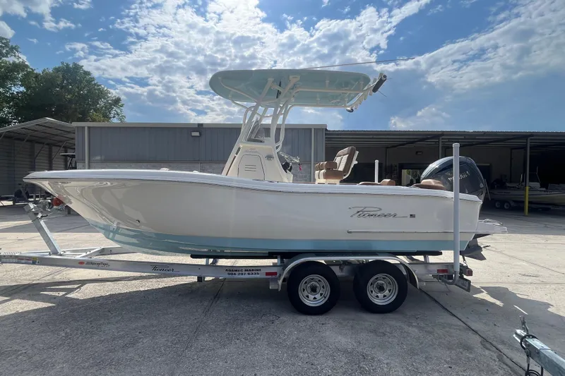 Slide: The Image of 2026 Pioneer 222 Islander boat on trailer, parked outdoors under a partly cloudy sky. - 15