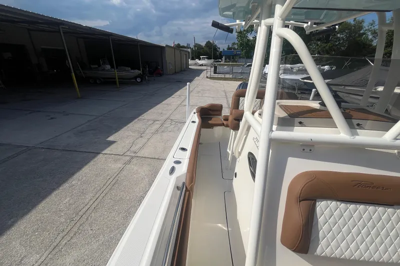 Slide: The Image of 2026 Pioneer 222 Islander boat with tan seating, docked in a marina under cloudy skies. - 32