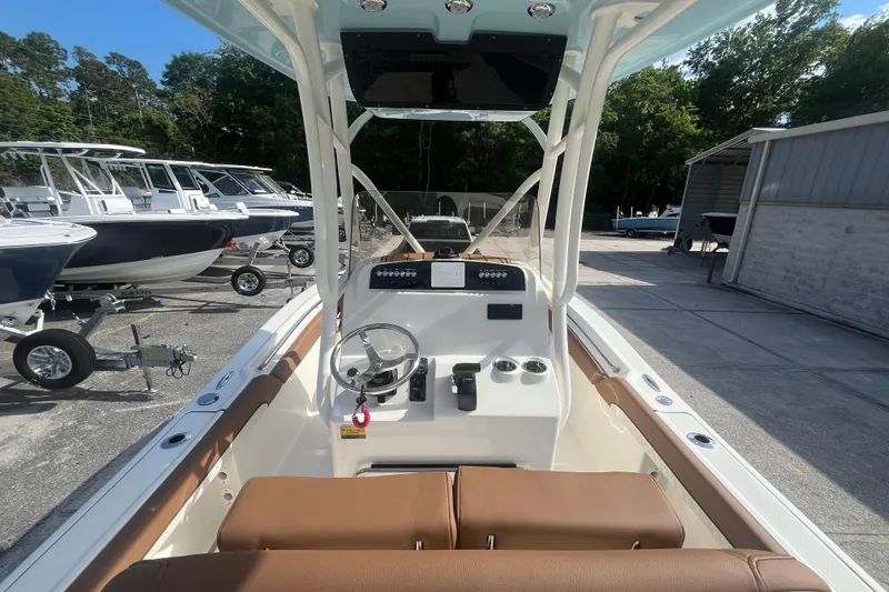 Slide: The Image of 2026 Pioneer 222 Islander boat interior with steering wheel and control panel, docked outdoors. - 34