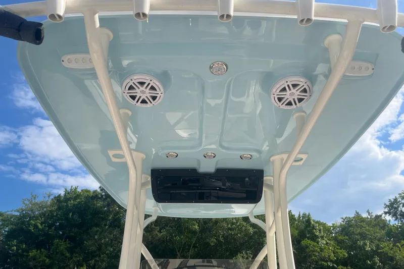 Slide: The Image of 2026 Pioneer 222 Islander boat canopy with speakers and rod holders, under a clear blue sky. - 38