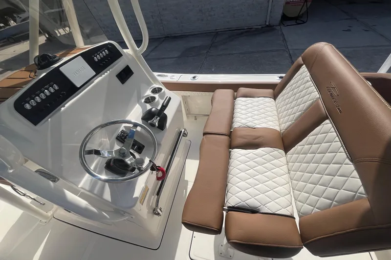 Slide: The Image of 2026 Pioneer 222 Islander boat interior with steering wheel and cushioned seating. - 39