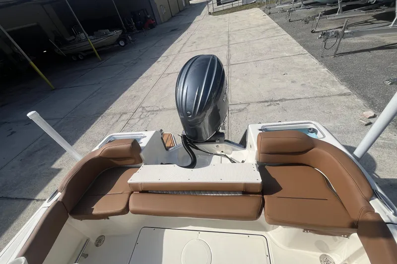 Slide: The Image of 2026 Pioneer 222 Islander boat with brown seating and outboard motor, docked on concrete. - 41