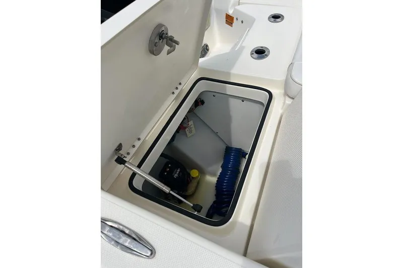 Slide: The Image of Open storage compartment on 2021 Skeeter SX2250 boat, featuring coiled hose and equipment. - 15