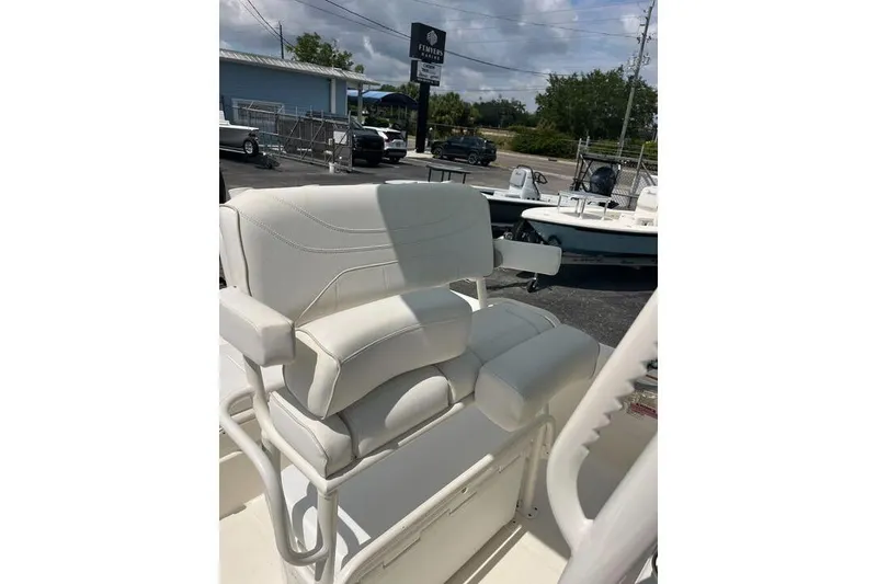Slide: The Image of 2021 Skeeter SX2250 boat with white cushioned seating and armrests, parked outdoors. - 16