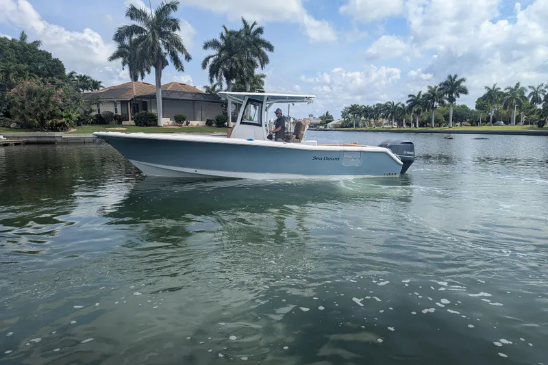 Slide: The Image of 2021 Sea Hunt Gamefish 30 boat on calm water, surrounded by palm trees. - 3
