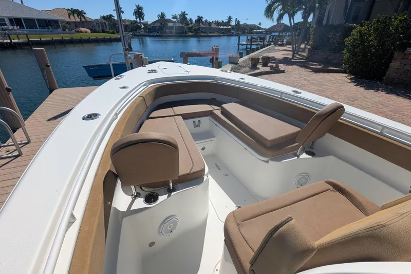 Slide: The Image of 2021 Sea Hunt Gamefish 30 boat with forward seating, docked by a scenic waterfront. - 6