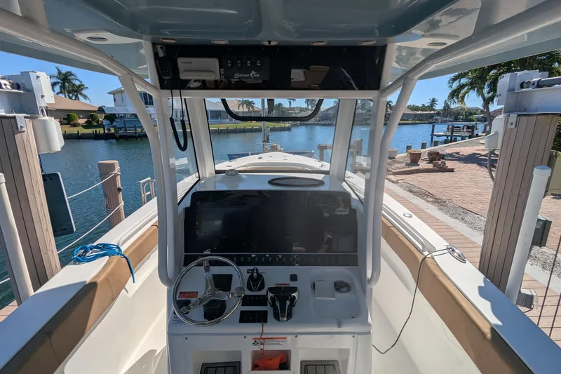 Slide: The Image of 2021 Sea Hunt Gamefish 30 boat with forward seating, docked by a scenic waterfront. - 9
