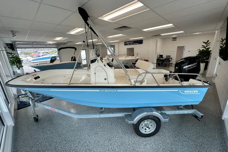Slide: The Image of 2026 Boston Whaler 150 Montauk boat in showroom, featuring sleek design and Mercury engine. - 17