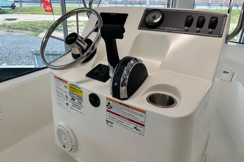 Slide: The Image of 2026 Boston Whaler 150 Montauk boat console with steering wheel and controls. - 22