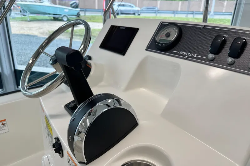 Slide: The Image of 2026 Boston Whaler 150 Montauk boat dashboard with steering wheel and controls. - 24