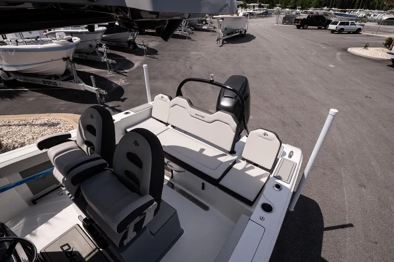 Slide: The Image of 2026 Sea Pro 245FLXR Sandbar boat interior with seating and console, parked in a marina. - 12