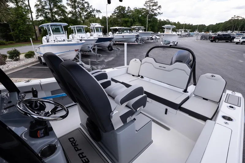 Slide: The Image of 2026 Sea Pro 245FLXR Sandbar boat interior with seating and steering wheel, parked in a marina. - 13