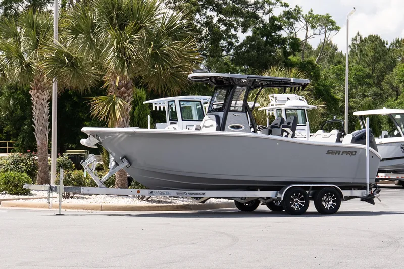 Slide: The Image of 2026 Sea Pro 245FLXR Sandbar boat on trailer, parked near palm trees. - 2