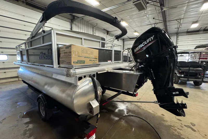 Slide: The Image of 2026 Sun Tracker Bass Buggy 16 XL Select pontoon boat with Mercury outboard motor in a garage. - 4