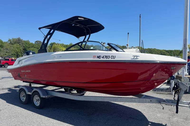 The Image of 2024 Bayliner VR6 Bowrider OB in red on a trailer, parked outdoors. - 0