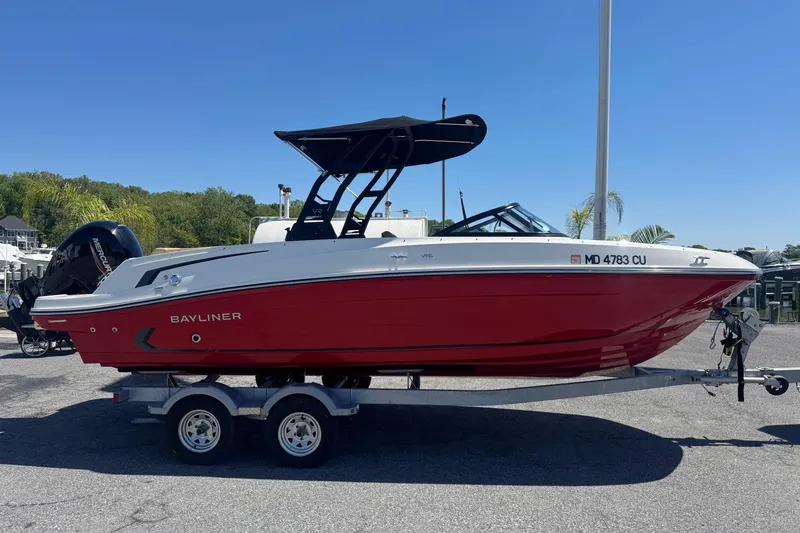 Slide: The Image of 2024 Bayliner VR6 Bowrider OB in red on a trailer, parked outdoors. - 2