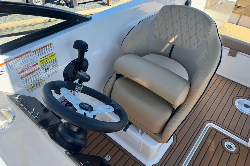 Slide: The Image of 2024 Bayliner VR6 Bowrider OB helm with steering wheel and beige captain's seat. - 5
