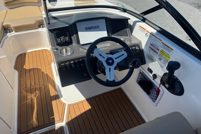 Slide: The Image of 2024 Bayliner VR6 Bowrider OB cockpit with steering wheel, Simrad display, and wood-style flooring. - 6