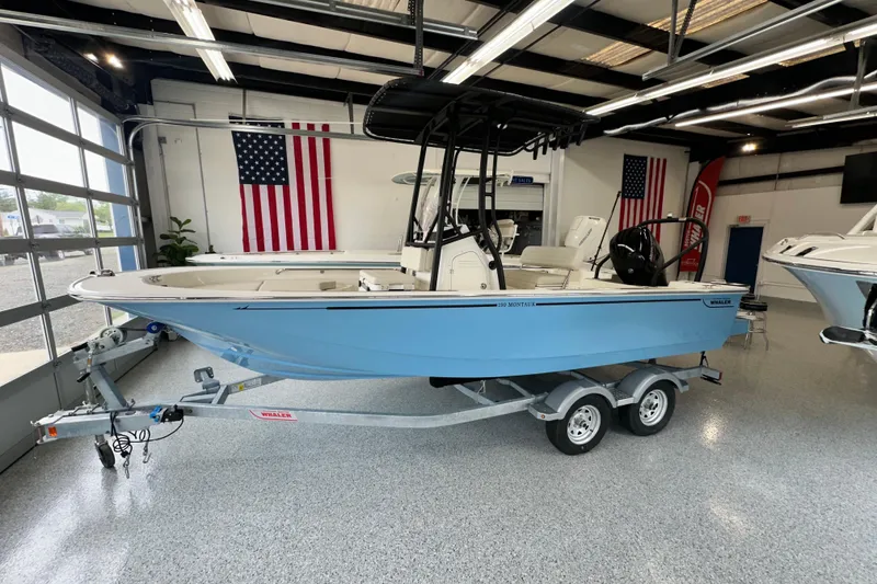 Slide: The Image of 2026 Boston Whaler 190 Montauk boat in showroom, featuring sleek design and dual-axle trailer. - 29
