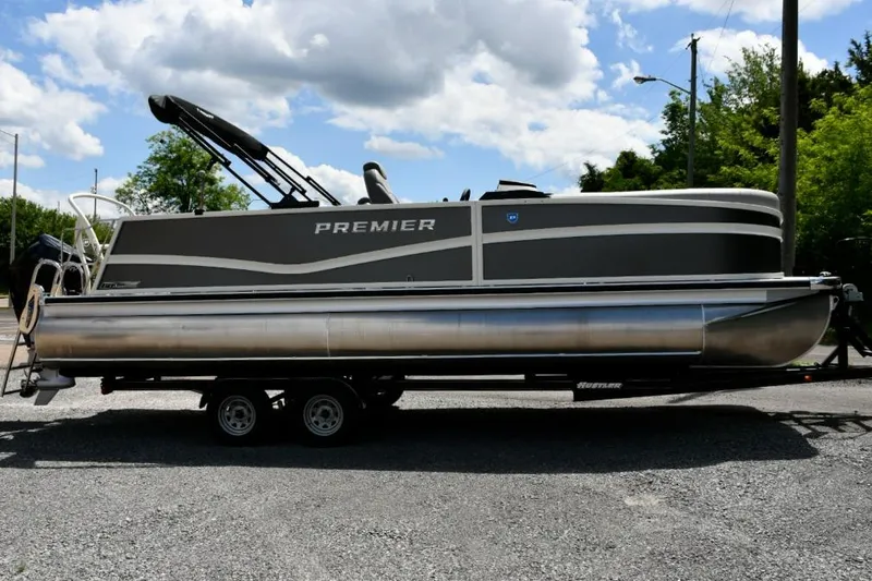 Slide: The Image of 2024 Premier 250 RL PTX pontoon boat on trailer under a cloudy sky. - 4