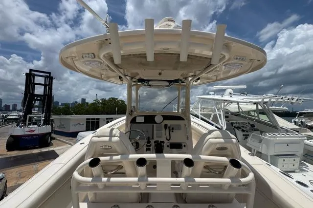 Slide: The Image of 2017 Grady-White Canyon 306 boat interior with helm and rod holders under a cloudy sky. - 2