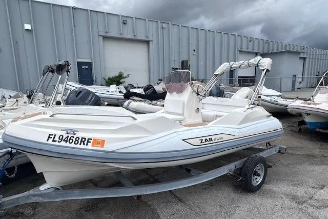 Slide: The Image of 2017 Zar Formenti 49 SL boat on trailer, parked outdoors near industrial building. - 2