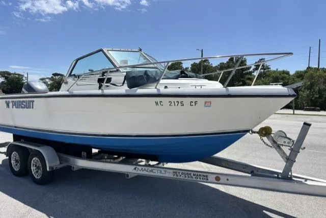 Slide: The Image of 1989 Pursuit 2260 Denali boat on trailer under clear blue sky. - 19