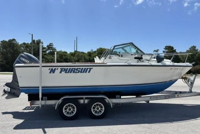 Slide: The Image of 1989 Pursuit 2260 Denali boat on trailer, featuring Yamaha engine, parked outdoors. - 20