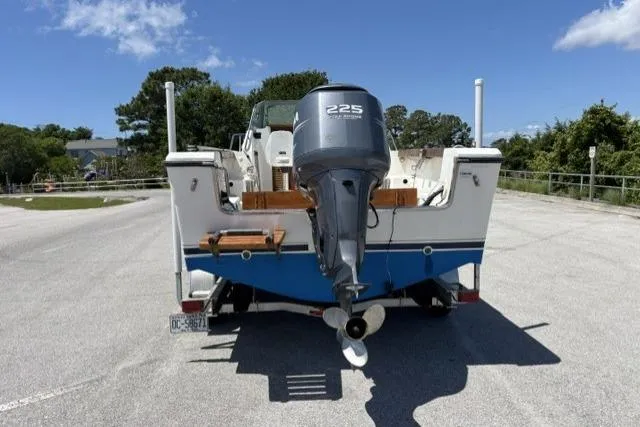 Slide: The Image of 1989 Pursuit 2260 Denali boat with 225 horsepower outboard motor, parked on a sunny day. - 23