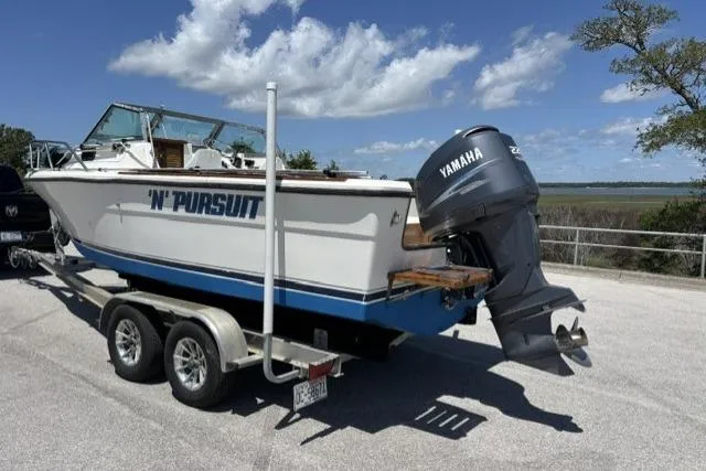 Slide: The Image of 1989 Pursuit 2260 Denali boat on trailer with Yamaha outboard motor, parked outdoors. - 24