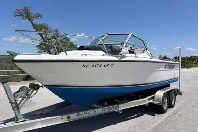 Slide: The Image of 1989 Pursuit 2260 Denali boat on trailer, parked outdoors under clear sky. - 26