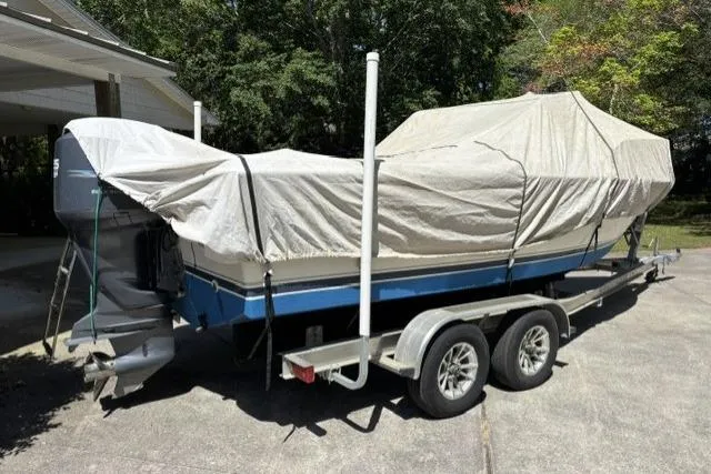 Slide: The Image of 1989 Pursuit 2260 Denali boat covered on trailer, parked outdoors. - 28