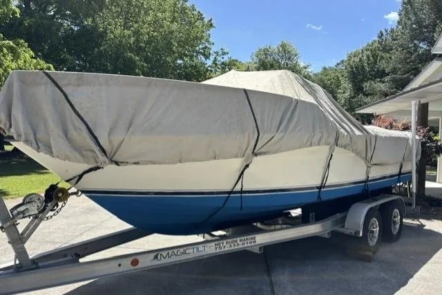 Slide: The Image of 1989 Pursuit 2260 Denali boat covered on trailer, parked outdoors. - 30