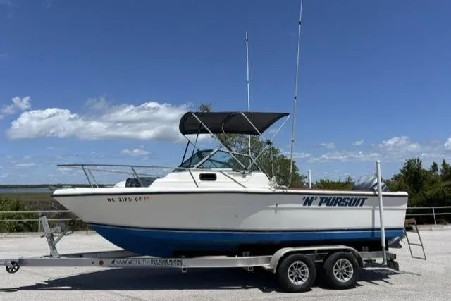 Slide: The Image of 1989 Pursuit 2260 Denali boat on trailer under clear blue sky. - 4