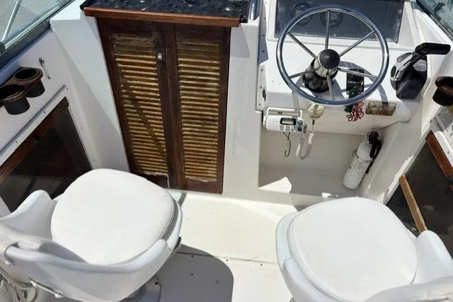 Slide: The Image of 1989 Pursuit 2260 Denali boat cockpit with steering wheel and two white seats. - 5