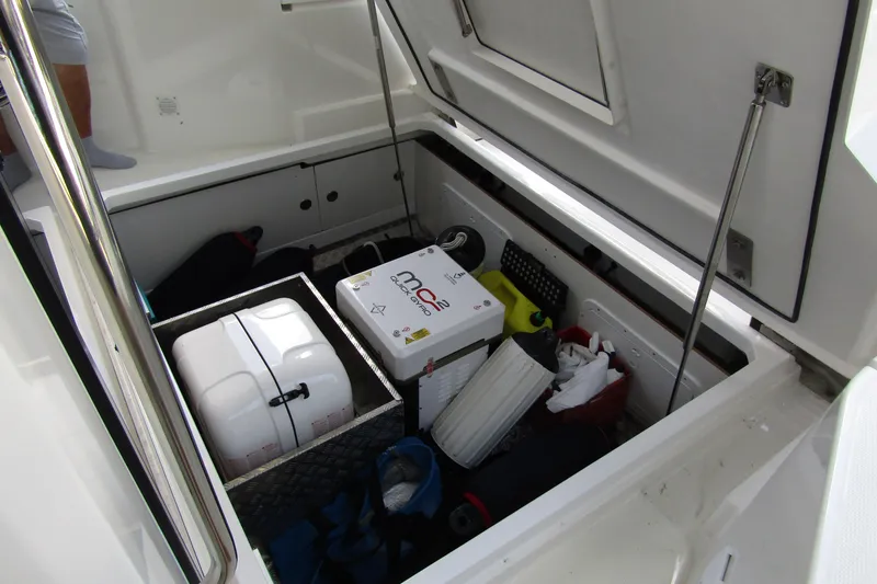Slide: The Image of Open storage compartment on 2024 Nimbus Commuter 11 boat, showing various equipment and supplies. - 16