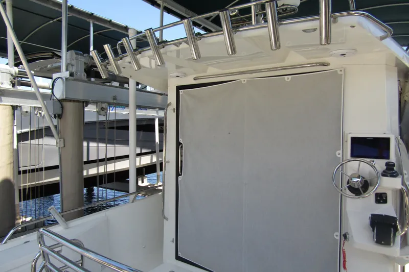 Slide: The Image of 2024 Nimbus Commuter 11 boat interior with steering wheel and rod holders at dock. - 19