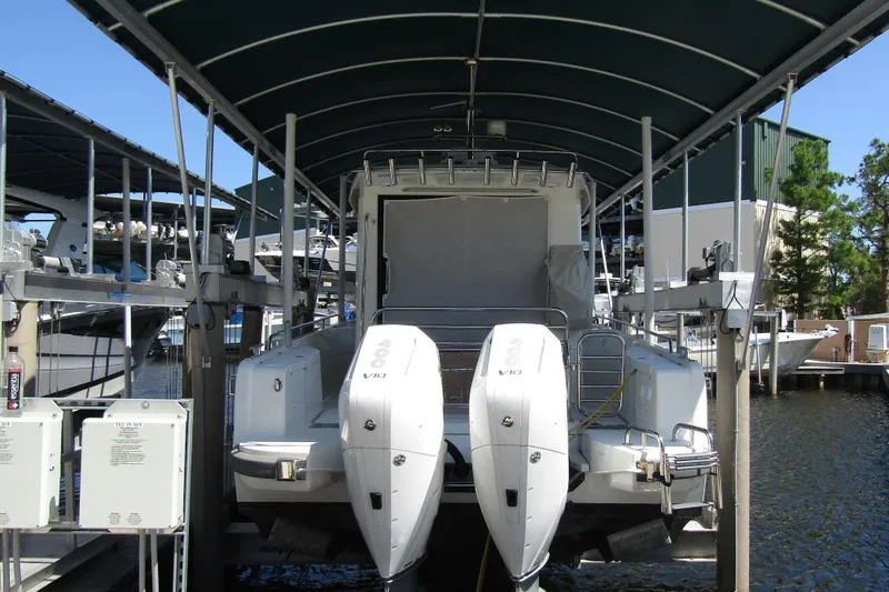 Slide: The Image of 2024 Nimbus Commuter 11 boat docked with dual outboard engines under a covered marina. - 2