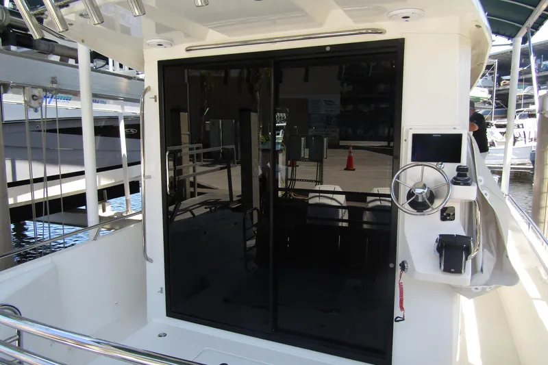 Slide: The Image of 2024 Nimbus Commuter 11 boat cockpit with steering wheel and sliding glass door. - 20