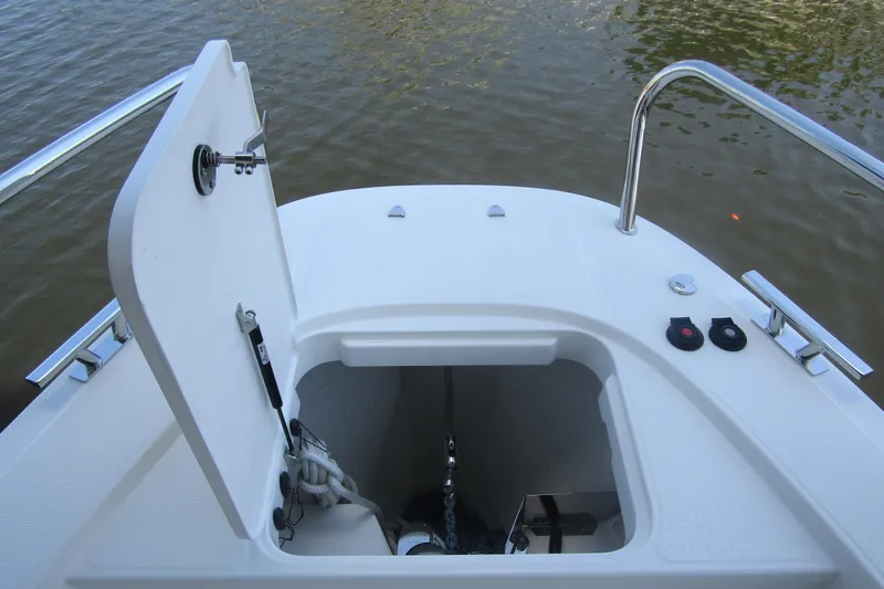 Slide: The Image of 2024 Nimbus Commuter 11 boat anchor compartment with open hatch on calm water. - 24