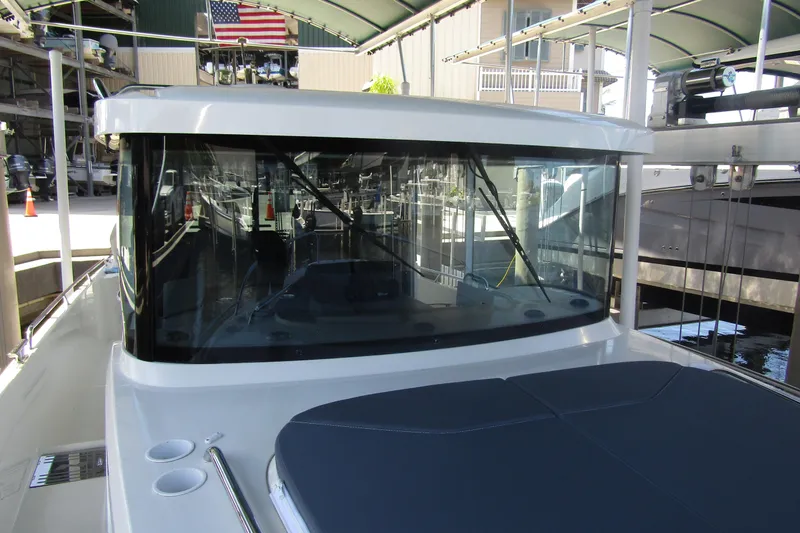 Slide: The Image of 2024 Nimbus Commuter 11 boat docked under a canopy with American flag. - 26
