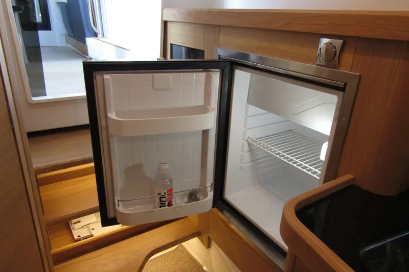 Slide: The Image of 2024 Nimbus Commuter 11 interior with open mini fridge, wooden cabinetry. - 50