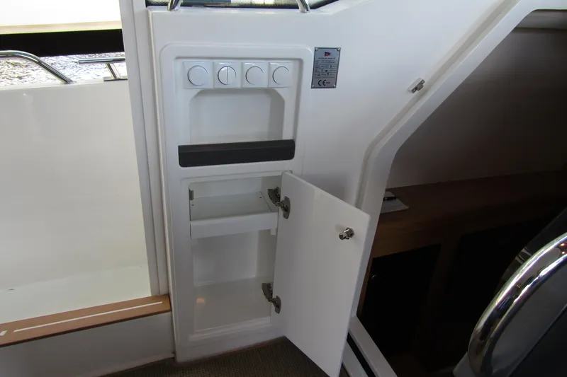 Slide: The Image of 2024 Nimbus Commuter 11 interior storage compartment with open door and control panel. - 68
