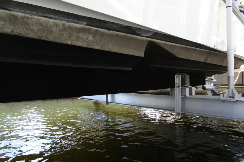 Slide: The Image of Underneath view of a 2024 Nimbus Commuter 11 boat on a lift above water. - 8