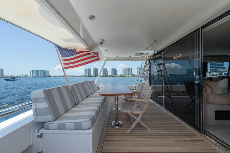 Slide: The Image of 2007 Pacific Mariner Pilothouse yacht deck with seating, table, and American flag, overlooking waterfront cityscape. - 37